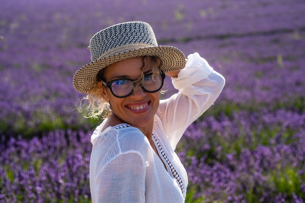 Ritratto di bella donna allegra di mezza età con campo di lavanda viola viola sullo sfondo - le persone di sesso femminile viaggiano e si divertono all'aperto nella stagione estiva per le vacanze in francia provenza