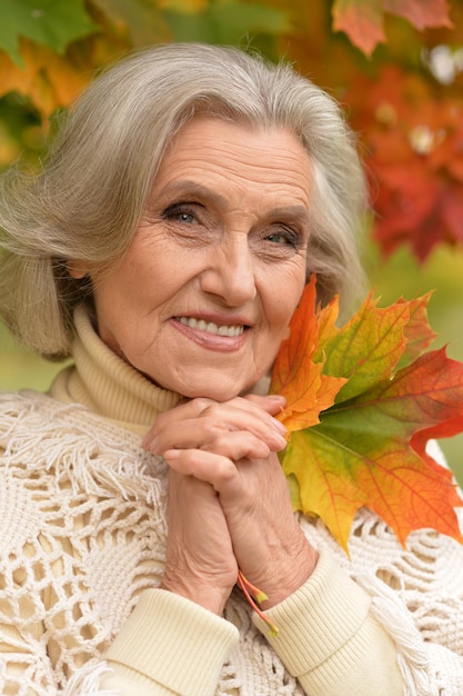 Ritratto di bella donna anziana che tiene le foglie d'autunno