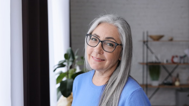 Ritratto di bella donna anziana dai capelli grigi sorridente che guarda l'obbiettivo.