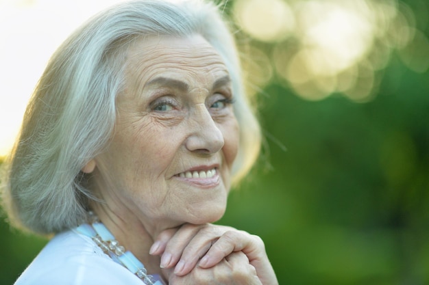 Ritratto di bella donna anziana sorridente nel parco di primavera