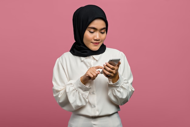 Ritratto di bella donna asiatica che indossa una camicia bianca e utilizza lo smartphone