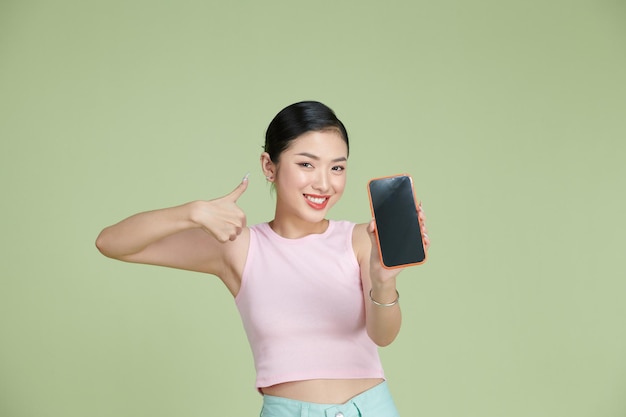 Ritratto di bella donna asiatica che mostra pollice in su e schermo dello smartphone