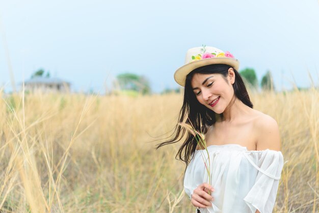 Ritratto di bella donna asiatica che sente il cappello fresco in mano al denim fieldwear con stivale marrone