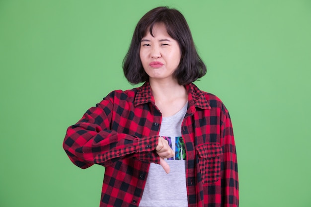 Ritratto di bella donna asiatica hipster con i capelli corti contro la chiave di crominanza o la parete verde