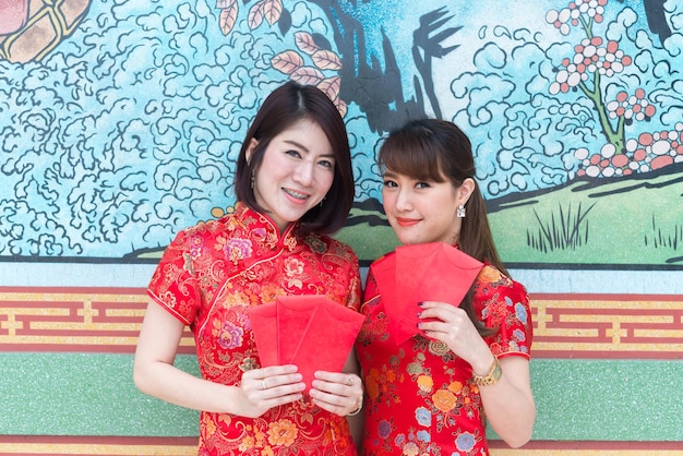 Ritratto di bella donna asiatica in abito Cheongsam con busta rossa in manoPopolo tailandeseFelice concetto di nuovo anno cinese