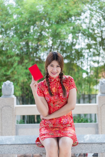 Ritratto di bella donna asiatica in abito Cheongsam con busta rossa in manoPopolo tailandeseFelice concetto di nuovo anno cinese