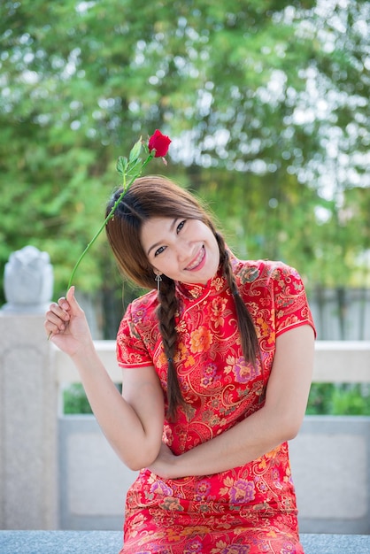 Ritratto di bella donna asiatica in abito Cheongsam con Red Rose in manoPopolo thailandeseFelice concetto di Capodanno cinese