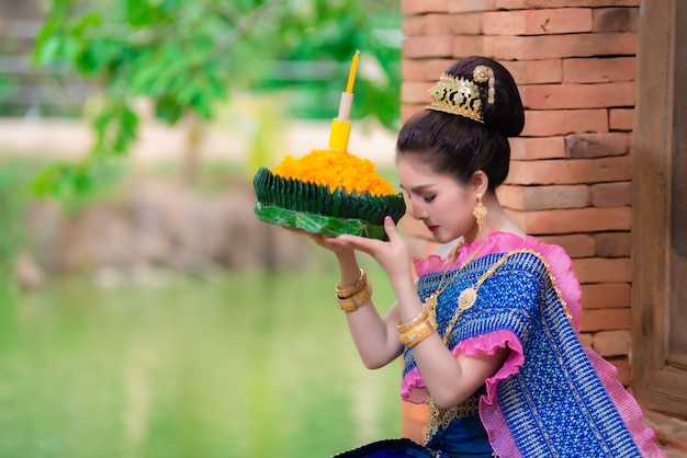 Ritratto di bella donna asiatica in abito tailandese tradizionale pregando tenere kratong per unirsi al festival loy kratong in thailandia