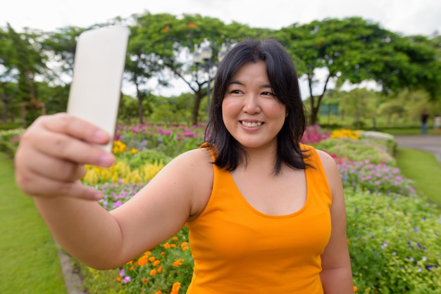 Ritratto di bella donna asiatica in sovrappeso rilassante presso il parco della città di Bangkok, Thailandia