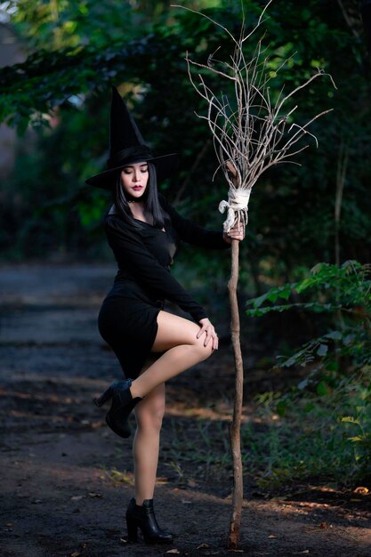 Ritratto di bella donna asiatica sexy indossare costume da strega nera con scopaConcetto di festival di Halloween