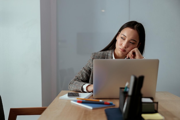 Ritratto di bella donna asiatica stanca di affari che lavora nel computer di uso dell'ufficio