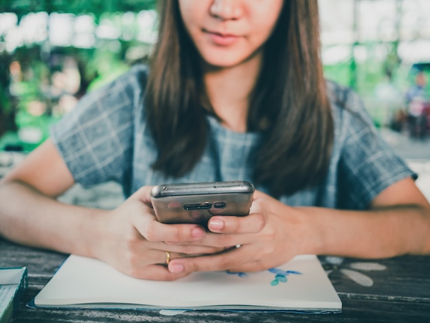 Ritratto di bella donna asiatica utilizzando smartphone sul tavolo di legno