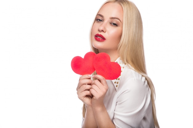 Ritratto di bella donna bionda con trucco luminoso e cuore rosso in mano