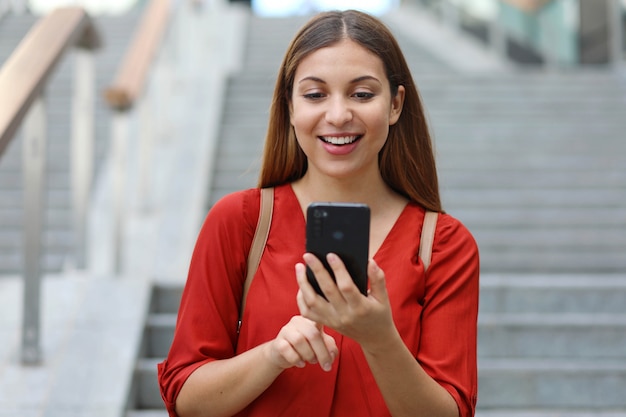 Ritratto di bella donna che cammina giù per le scale tenendo il suo telefono