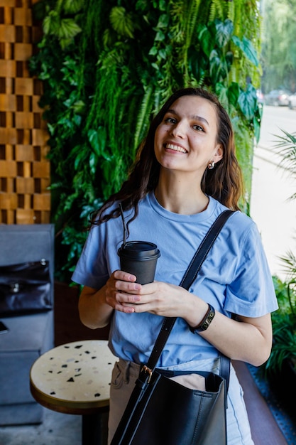 Ritratto di bella donna che mangia tazza di caffè nella caffetteria