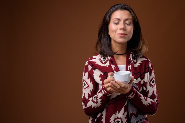 Ritratto di bella donna che tiene la tazza di caffè pronta per l'inverno