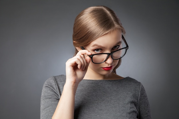 Ritratto di bella donna con gli occhiali che flirta con la macchina fotografica