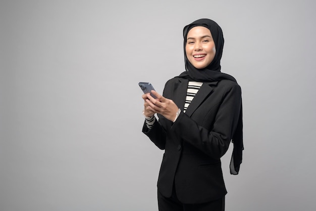 Ritratto di bella donna con hijab tramite cellulare su sfondo bianco