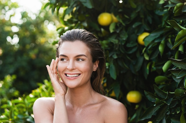 Ritratto di bella donna con la pelle liscia contro alberi di limoni