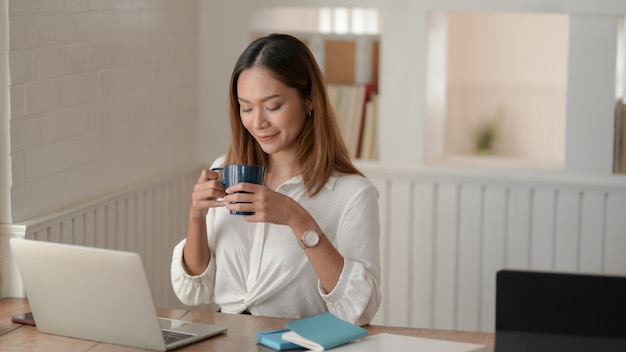 Ritratto di bella donna d'affari asiatiche, lavorando sul suo progetto e bere un caffè