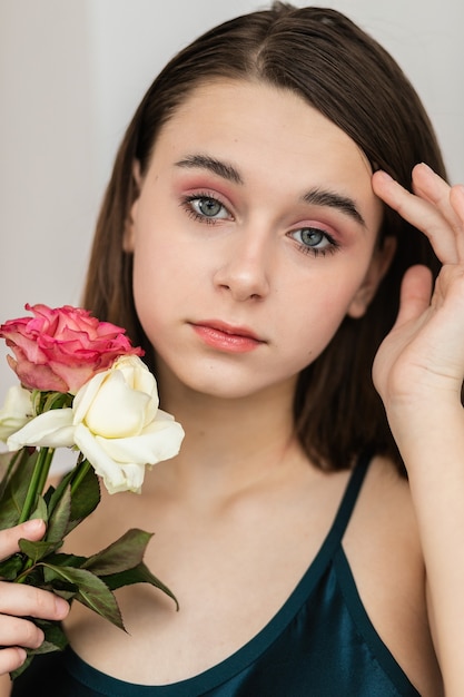 Ritratto di bella donna dai capelli scuri con fiori. Foto di moda, bella bambina con rosa rosa