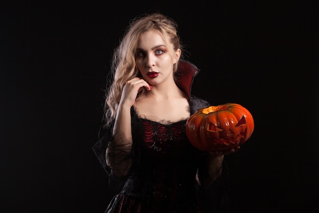 Ritratto di bella donna del vampiro con la zucca di Halloween. Seducente donna vampiro.