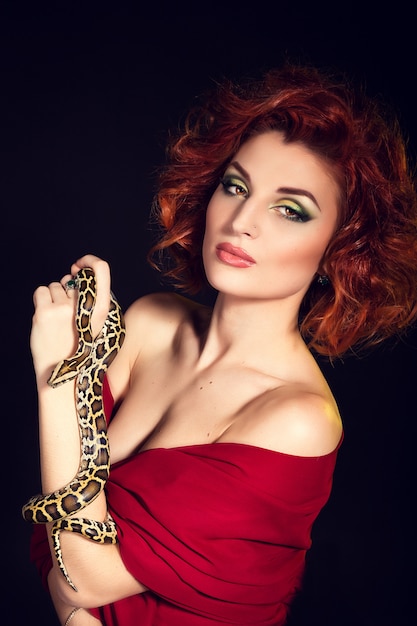 Ritratto di bella donna in studio con un serpente pericoloso