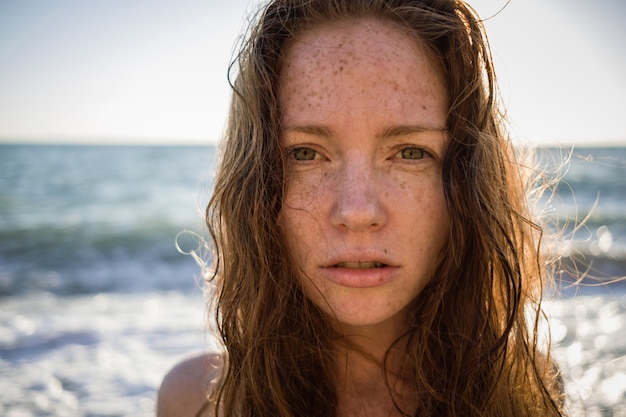 Ritratto di bella donna lentigginosa sulla spiaggia al tramonto