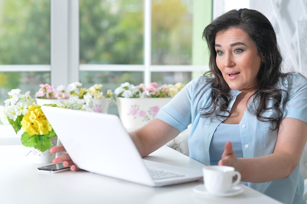 Ritratto di bella donna matura che per mezzo del computer portatile