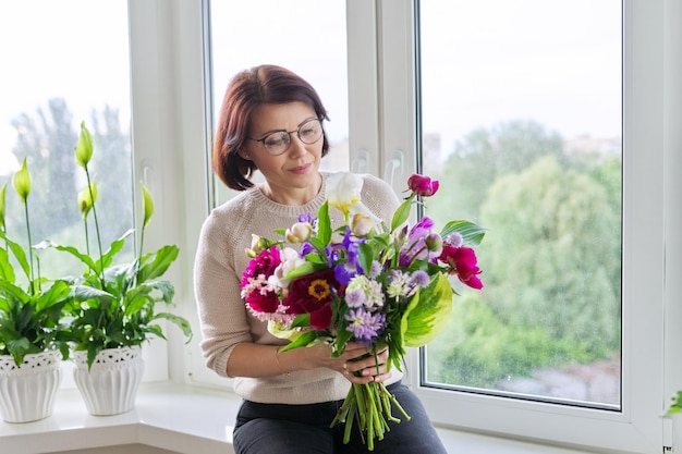 Ritratto di bella donna matura con bouquet a casa