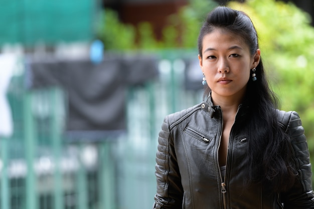 Ritratto di bella donna ribelle asiatica che indossa giacca di pelle per le strade all'aperto