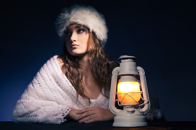 Ritratto di bella donna seduta con lanterna su sfondo scuro