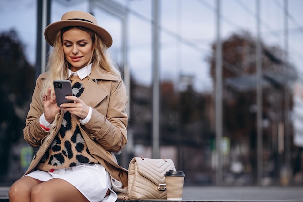 Ritratto di bella donna seduta sulle scale e utilizzando il telefono