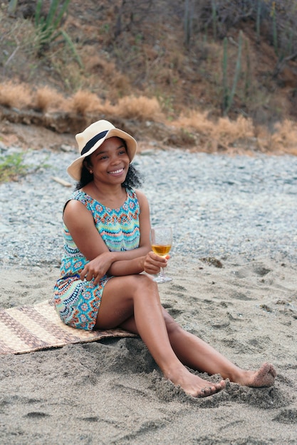 Ritratto di bella donna sorridente con vino bianco in spiaggia