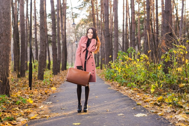 Ritratto di bella donna sorridente in cappotto beige con borsa marrone