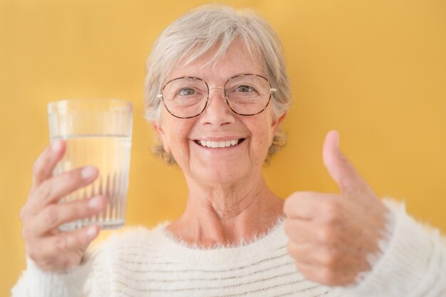 Ritratto di bella donna sorridente senior adulta che guarda l'obbiettivo in possesso di un bicchiere pieno d'acqua