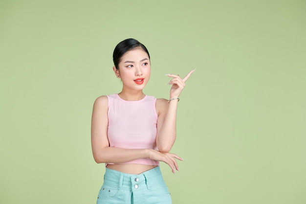 Ritratto di bella giovane donna asiatica che punta una mano con il dito sul lato con la faccia sorridente