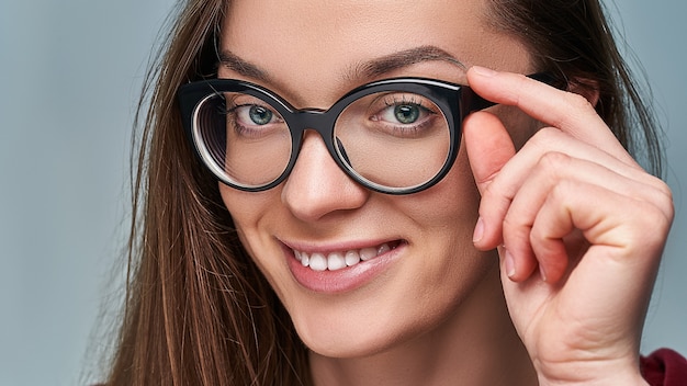 Ritratto di bella giovane donna caucasica sorridente del brunette che porta i vetri neri dell'orlo