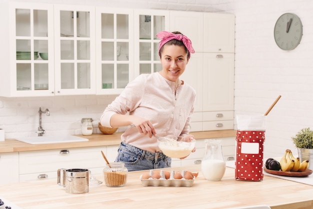 Ritratto di bella giovane donna che mangia prima colazione nella cucina.