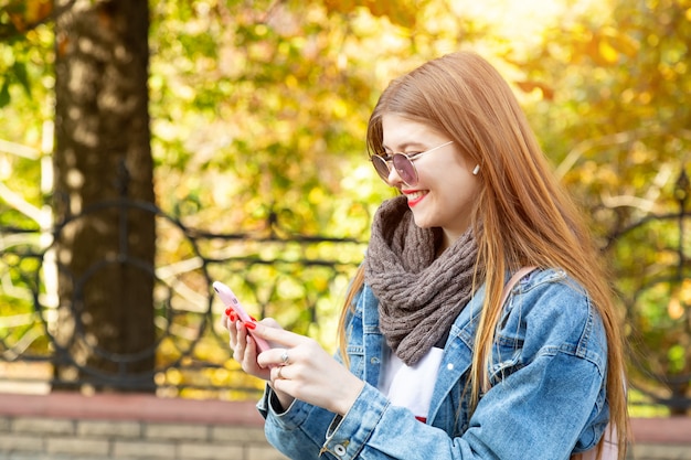 Ritratto di bella giovane donna che utilizza il suo telefono cellulare nel parco