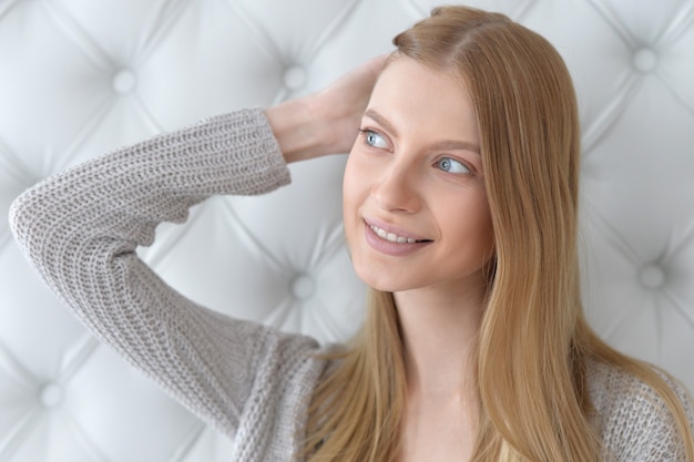 Ritratto di bella giovane donna con gli occhi azzurri profondi e le mani nei capelli