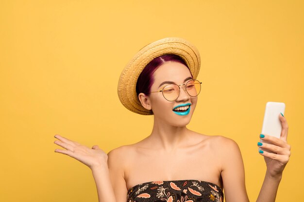 Ritratto di bella giovane donna con trucco luminoso isolato su sfondo giallo studio