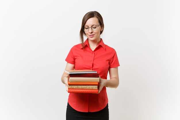 Ritratto di bella giovane donna dell'insegnante di affari in camicia rossa, gonna nera e vetri che tengono i libri in mani isolate su fondo bianco. Istruzione o insegnamento nel concetto di università delle scuole superiori