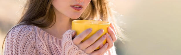 Ritratto di bella giovane donna in elegante maglione lavorato a maglia in piedi sulla foresta autunnale dorata in una giornata di sole Tempo per rilassarsi e prendere un caffè