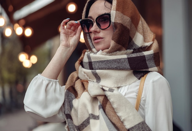 Ritratto di bella giovane donna in occhiali da sole con la testa della copertura della sciarpa Donna alla moda