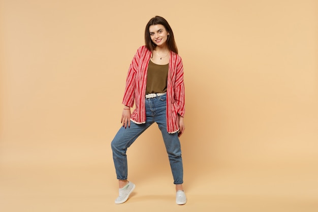 Ritratto di bella giovane donna sorridente in vestiti casuali che stanno guardando la macchina fotografica isolata sul fondo beige pastello della parete in studio. Persone sincere emozioni, concetto di stile di vita. Mock up copia spazio.