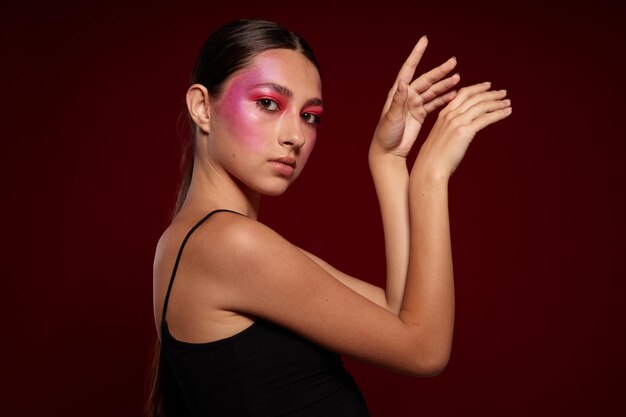 Ritratto di bella giovane donna trucco emozioni cosmetici cura dei capelli mascara sfondo rosa inalterato