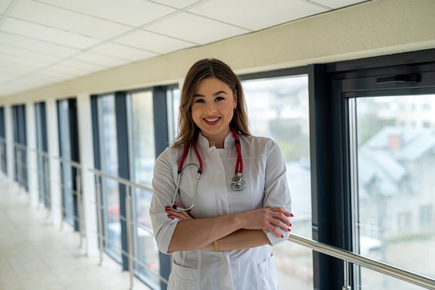 Ritratto di bella infermiera sorridente in uniforme bianca con lo stetoscopio che guarda l'obbiettivo e sorridente. Studente di medicina