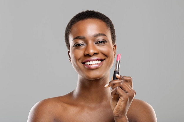 Ritratto di bella ragazza afro con rossetto rosa in mano