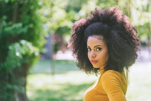 Ritratto di bella ragazza afro in un giardino. Avvicinamento. Messa a fuoco selettiva.